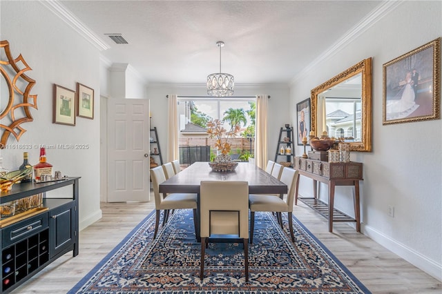 dining room with light wood-type flooring, baseboards, ornamental molding, and a chandelier