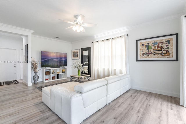 living room featuring light wood-style floors, visible vents, and ornamental molding