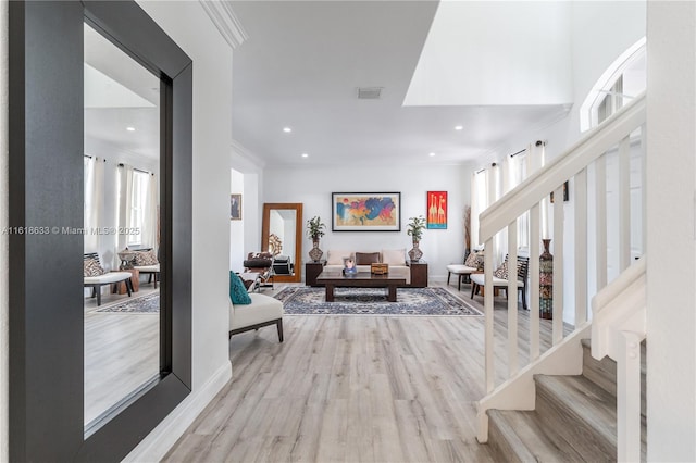 foyer with stairway, visible vents, wood finished floors, and ornamental molding