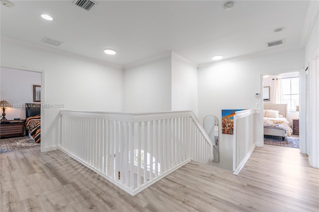 corridor featuring ornamental molding, visible vents, an upstairs landing, and wood finished floors