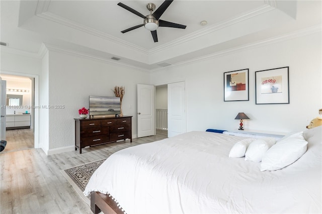 bedroom featuring wood finished floors, a raised ceiling, visible vents, and crown molding