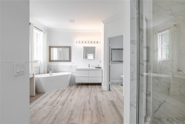 full bath featuring ornamental molding, a wealth of natural light, a freestanding tub, and a marble finish shower