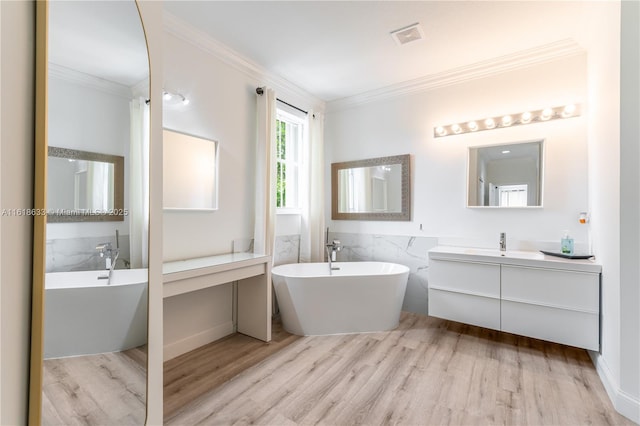 full bath with wood finished floors, vanity, visible vents, a freestanding bath, and crown molding