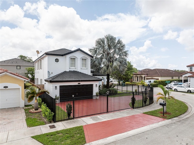 mediterranean / spanish home with a garage, a fenced front yard, a tiled roof, decorative driveway, and stucco siding