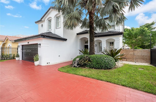 mediterranean / spanish-style home featuring a front lawn and a garage