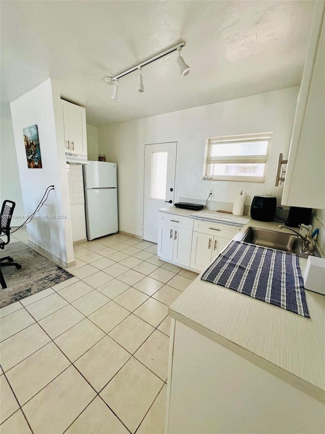 kitchen with sink, light tile patterned flooring, white cabinets, and white fridge