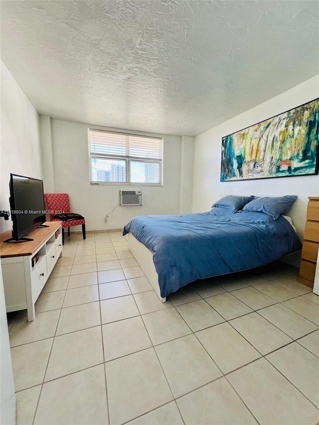 tiled bedroom with a wall mounted air conditioner and a textured ceiling