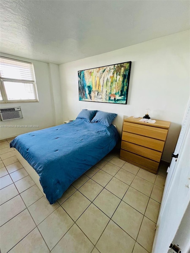 tiled bedroom with a textured ceiling and a wall mounted AC