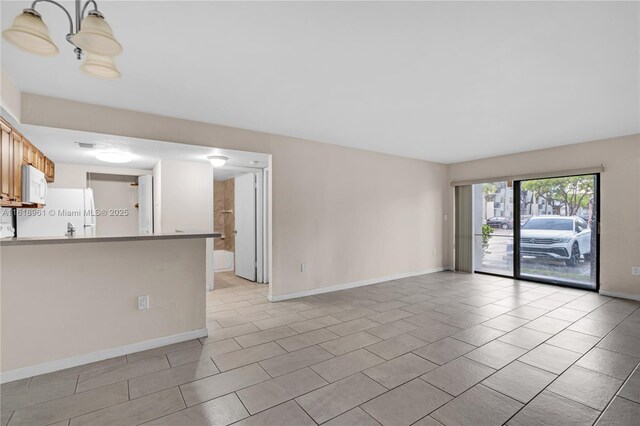 unfurnished room with an inviting chandelier and light tile patterned flooring