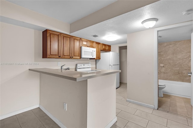 kitchen with light tile patterned flooring, a textured ceiling, kitchen peninsula, and white appliances