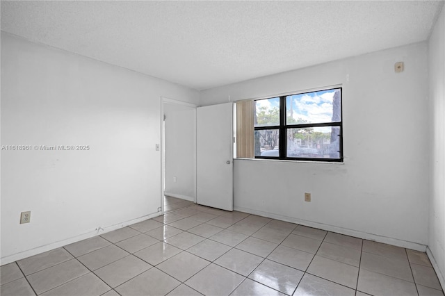 unfurnished room with light tile patterned floors and a textured ceiling