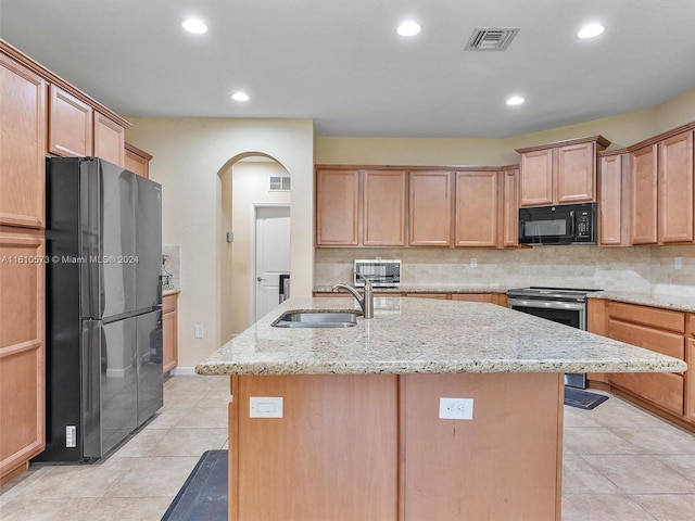 kitchen with tasteful backsplash, black appliances, sink, light stone counters, and a kitchen island with sink