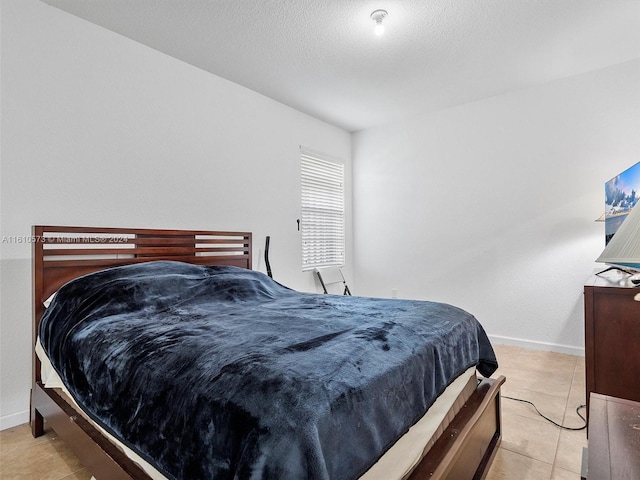 bedroom featuring a textured ceiling and light tile patterned floors