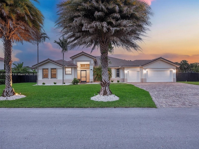 ranch-style house with a garage and a lawn