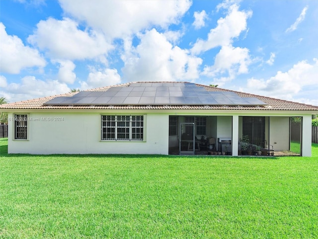 back of property featuring a yard, solar panels, and a sunroom