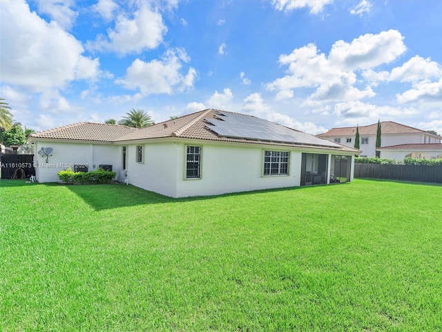 rear view of property with solar panels, a lawn, and a sunroom