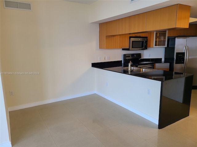 kitchen with sink, light tile patterned flooring, kitchen peninsula, and appliances with stainless steel finishes