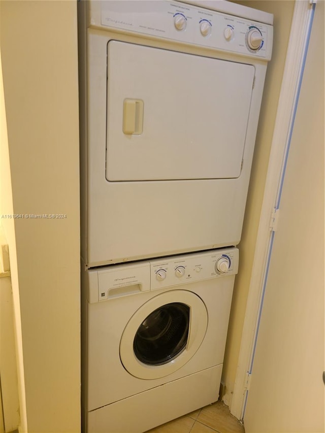 laundry area with stacked washer / dryer and light tile patterned floors