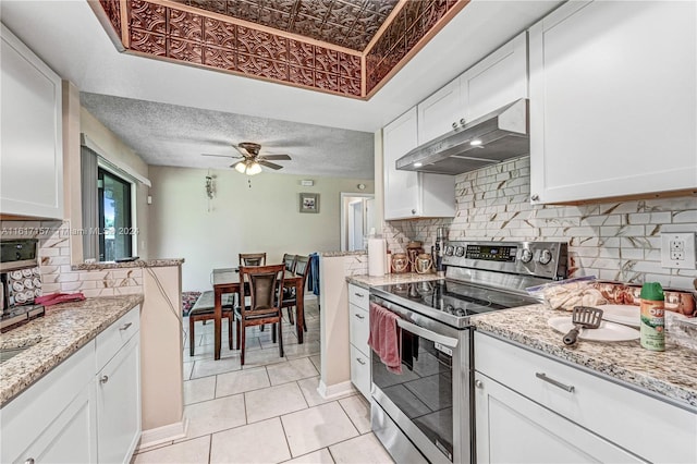 kitchen featuring backsplash, exhaust hood, stainless steel range with electric stovetop, white cabinetry, and ceiling fan