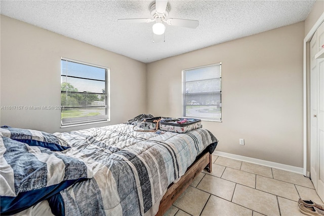 tiled bedroom with a textured ceiling and ceiling fan