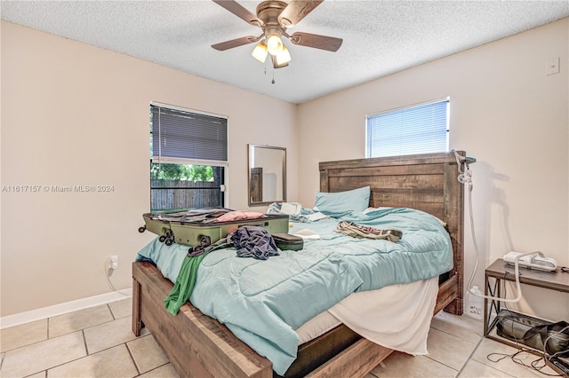 tiled bedroom with multiple windows, a textured ceiling, and ceiling fan