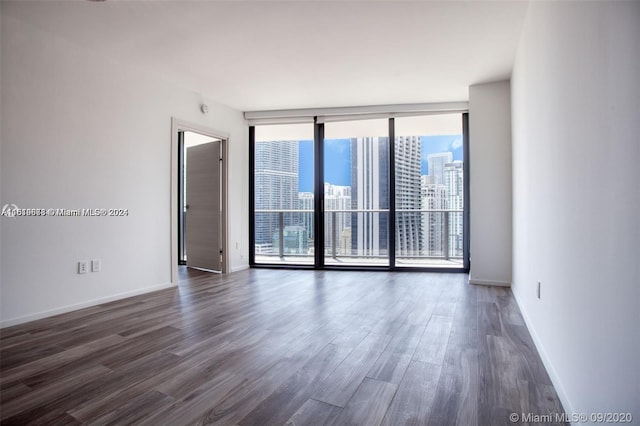 unfurnished room featuring a wall of windows and dark hardwood / wood-style floors