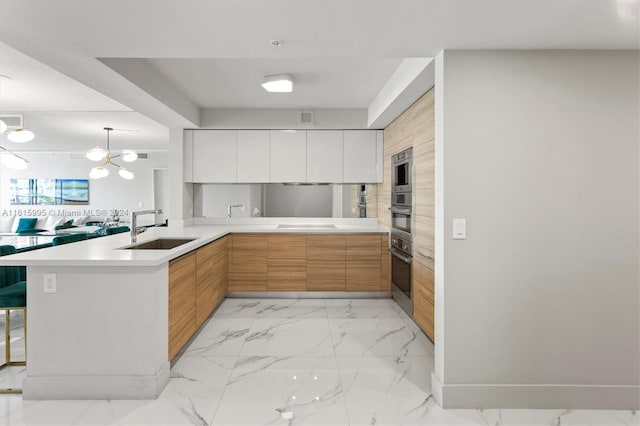 kitchen featuring light tile patterned flooring, white cabinetry, sink, and kitchen peninsula