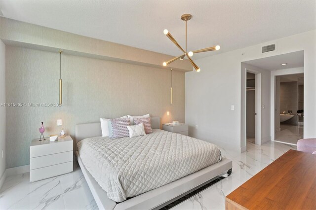 tiled bedroom featuring ensuite bathroom, a notable chandelier, a closet, and a spacious closet