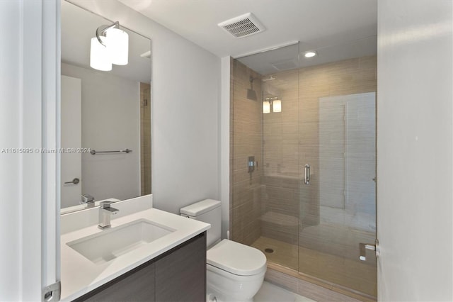 bathroom with vanity, toilet, and a shower with door