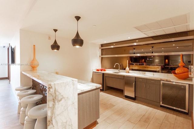 kitchen with dishwasher, light stone countertops, light hardwood / wood-style flooring, and hanging light fixtures