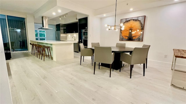 dining space with crown molding, a notable chandelier, and light hardwood / wood-style flooring