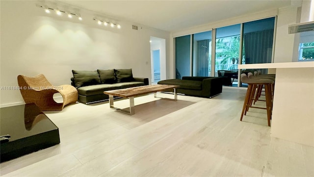 living room featuring a wall of windows, track lighting, bar, and a healthy amount of sunlight