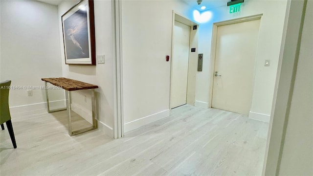 hallway featuring light wood-type flooring and elevator