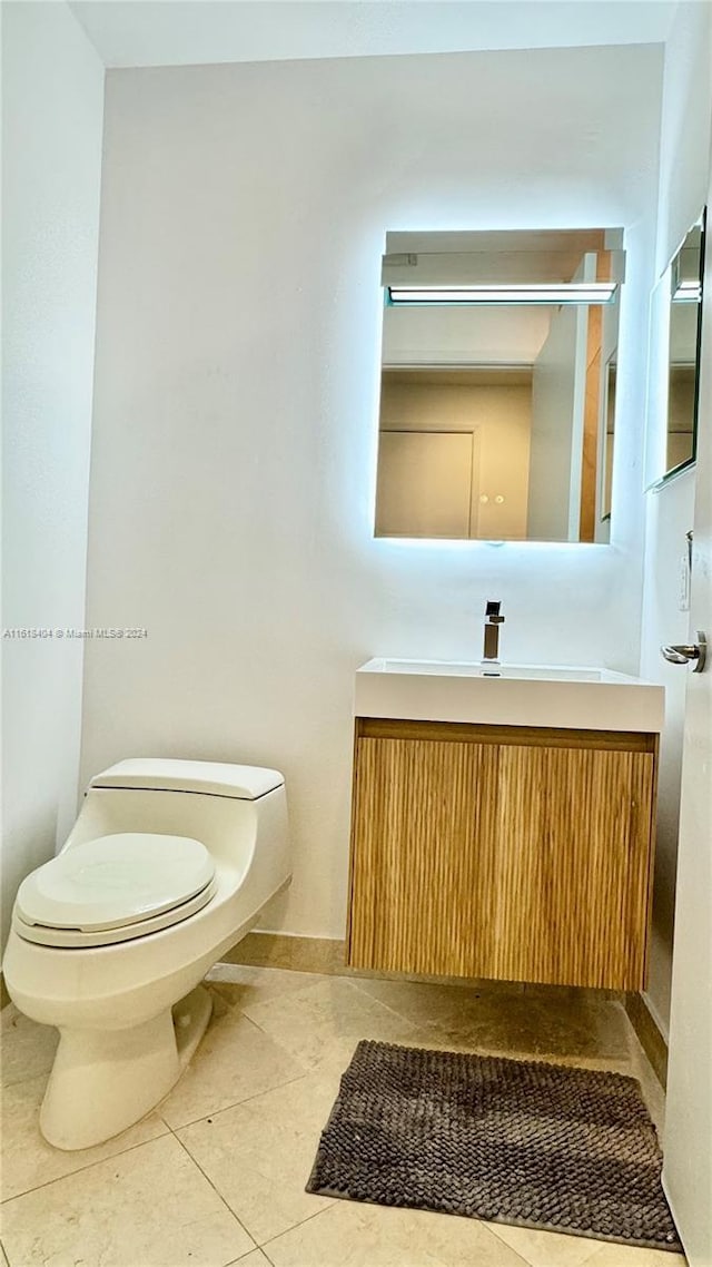 bathroom with toilet, vanity, and tile patterned flooring