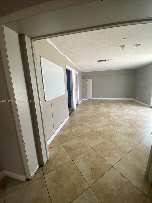 corridor with a textured ceiling and light tile patterned floors