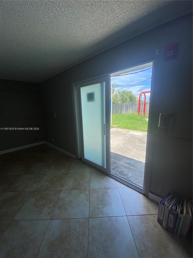 doorway to outside with a textured ceiling and tile patterned floors