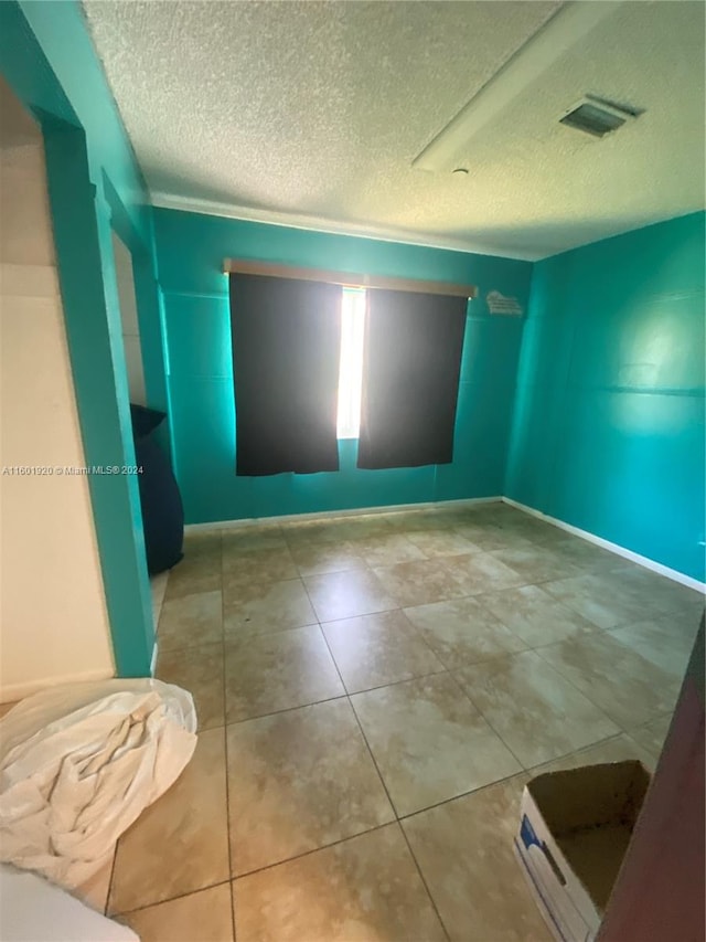 tiled spare room with a textured ceiling