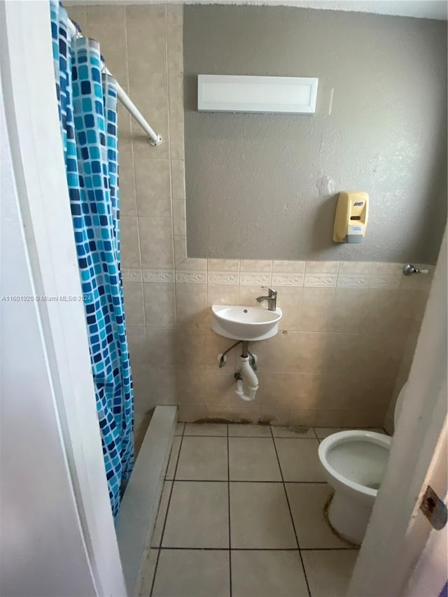 bathroom with tile patterned floors, sink, tile walls, and toilet