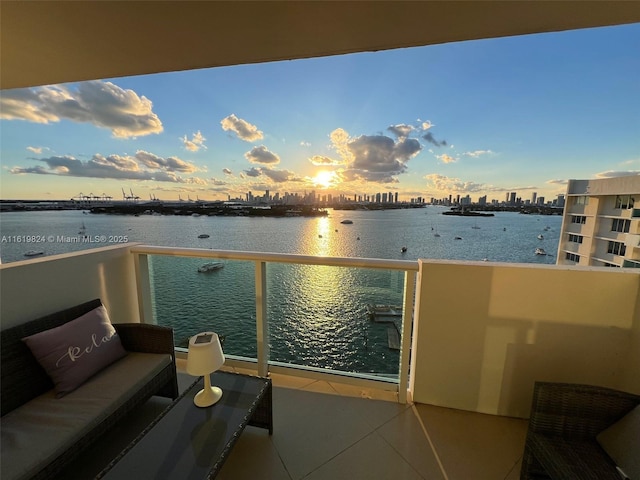 balcony featuring a water view, an outdoor living space, and a city view