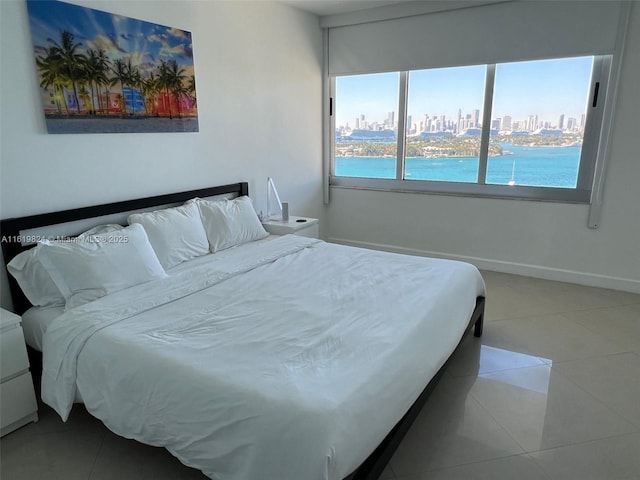 bedroom featuring tile patterned flooring, a view of city, and baseboards