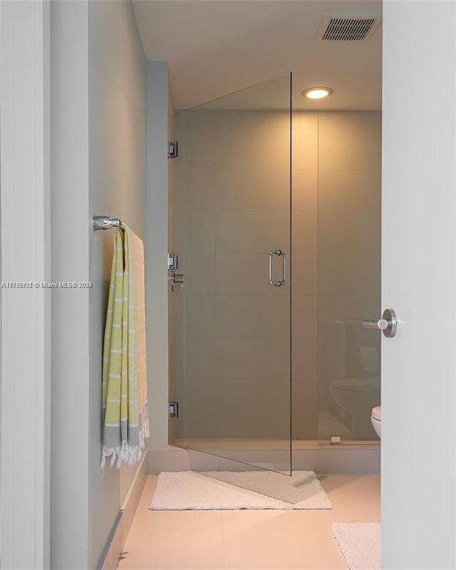 bathroom featuring an enclosed shower, tile patterned flooring, and toilet