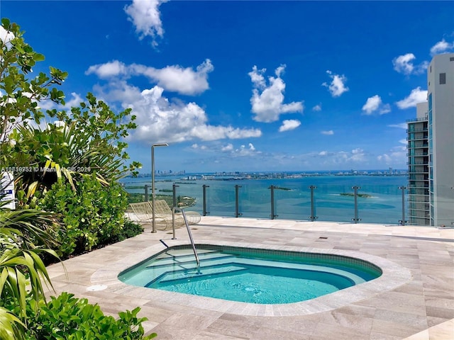 view of swimming pool with an in ground hot tub, a water view, and a patio area