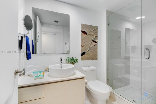 bathroom with a shower with shower door, vanity, and toilet