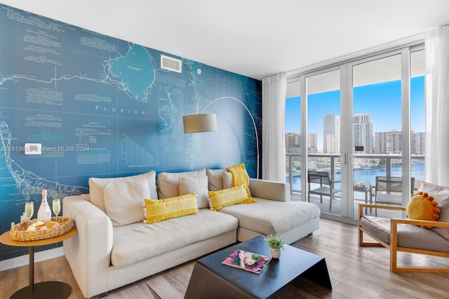 living room with a water view, wood-type flooring, and expansive windows