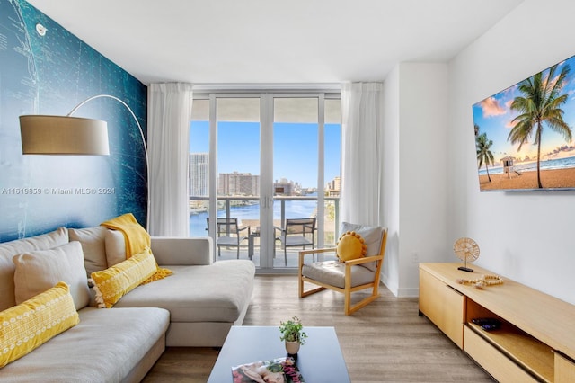 living room with hardwood / wood-style flooring, a water view, french doors, and a wall of windows