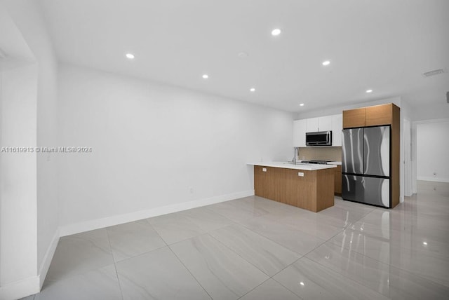 kitchen featuring appliances with stainless steel finishes, decorative backsplash, white cabinets, light tile patterned floors, and a center island