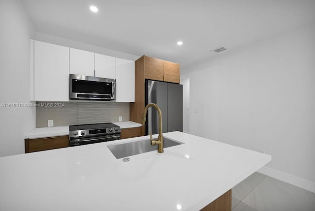 kitchen featuring sink, light tile patterned floors, decorative backsplash, white cabinetry, and stainless steel appliances