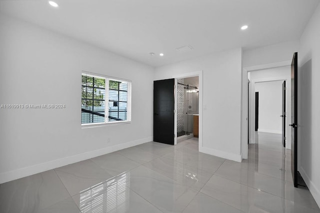 unfurnished bedroom featuring ensuite bathroom and light tile patterned flooring