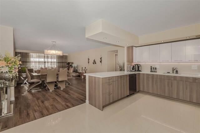 kitchen featuring white cabinetry, kitchen peninsula, an inviting chandelier, hardwood / wood-style floors, and decorative light fixtures