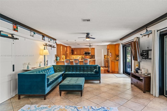 living room with a textured ceiling, ceiling fan, and light tile patterned floors